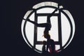 The dark silhouette of a beautiful woman with child on the background of the round window. yoga, acrobatics. Royalty Free Stock Photo