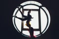 The dark silhouette of a beautiful woman with child on the background of the round window. yoga, acrobatics. Royalty Free Stock Photo