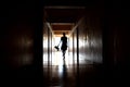 A dark silhouette of a child with a Teddy bear. One child with a dark long corridor. Spooky scary hallway. The house is haunted. Royalty Free Stock Photo