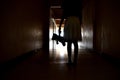 A dark silhouette of a child with a Teddy bear. One child with a dark long corridor. Spooky scary hallway. The house is haunted. Royalty Free Stock Photo