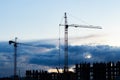 Dark silhouette of a construction crane, dark blue twilight sky. Construction of a residential building, evening industry