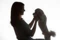 Dark silhouette of a girl with a bichon puppy