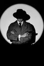 A dark silhouette of a male detective in a coat and hat with a gun in his hands in the noir style. A dramatic portrait Royalty Free Stock Photo