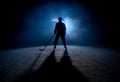 Dark silhouette of a male hockey player in a uniform, helmet and skates with a stick on the ice arena with smoke and