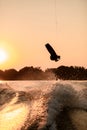 dark silhouette of man holding rope and making jump on wakeboard at sunset. Royalty Free Stock Photo