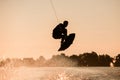 dark silhouette of man making trick in jump time with wakeboard on sky background. Royalty Free Stock Photo