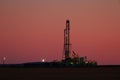 Black silhouette of oil drilling rig in the field at night