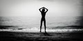 Dark silhouette of slim girl on the sea beach with hands by head, bw photo Royalty Free Stock Photo