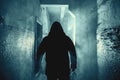 Dark silhouette of strange danger man in hood in back light with smoke or fog in scary grunge corridor or tunnel Royalty Free Stock Photo