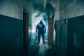 Dark silhouette of strange danger man in hood in back light with smoke or fog in scary grunge corridor or tunnel Royalty Free Stock Photo