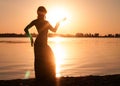 Dark silhouette of woman dancing trible near river coast