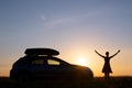 Dark silhouette of woman driver standing near her car on grassy field enjoying view of bright sunset. Young female Royalty Free Stock Photo