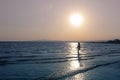 Dark silhouette of young woman seen from far away, going alone by the sea on the background of sunset. Lanscape in