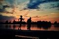 Dark silhouettes of scamper runners while sunset near lake.
