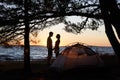 Young couple man and woman having rest at tourist tent and burning campfire on sea shore near forest Royalty Free Stock Photo