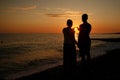 dark silhouettes of young people on the background of the sunset on the sea