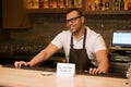 A dark-skinned bartender smiles at a visitor, there is a message on the bar counter prohibiting the sale of alcohol to Royalty Free Stock Photo