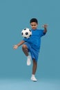 Dark skinned boy knee-up soccer ball