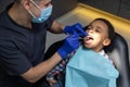 Dark-skinned boy looking scared while doctor checking his teeth