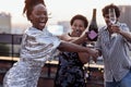 Dark-skinned girl pours champagne into glasses of her multinational friends