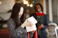 Happy Chinese girl received a gift from an African in a cafe