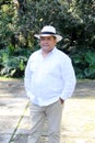 Dark-skinned Latino 50 year old man dressed in guayabera and hat, traditional Latin American dress, enjoys a walk outdoors