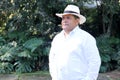 Dark-skinned Latino 50 year old man dressed in guayabera and hat, traditional Latin American dress, enjoys a walk outdoors