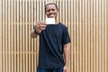 Dark-skinned man in black T-shirt showing blank business card to camera. Royalty Free Stock Photo