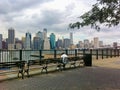 Dark skinned man on park bench looks at water near Brooklyn Bridge Royalty Free Stock Photo