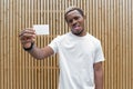 Dark-skinned man in white T-shirt showing blank business card to camera. Royalty Free Stock Photo