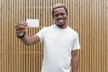 Dark-skinned man in white T-shirt showing blank business card to camera. Royalty Free Stock Photo