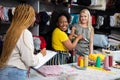 The dark-skinned seamstress gives the measured measurements to her helper.