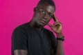 Dark-skinned serious young guy holds his fingers at his temple