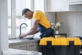 Dark-skinned service man working in the kitchen and looking concentrated on work