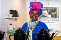 A dark-skinned woman in national costume sells tea