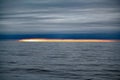 Orange and yellow colors of sunset in small stripe on horizont over dark sea with dark cloudy sky, Antarctic Ocean, Antarctica Royalty Free Stock Photo