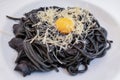 dark spaghetti pasta with egg and cheese on a white plate Royalty Free Stock Photo