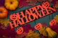 Dark and spooky Happy Halloween Greeting, top view photograph of fall leaves, pumpkin and jack o lantern with text