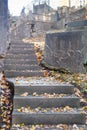 Dark stairway made of stone with leaves on cemetery, uphill. Autumn.