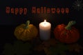 A dark still life for Halloween: two pumpkins and a candle between them. Royalty Free Stock Photo