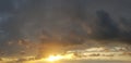 Dark storm cloud with golden sun on dramatic sunset sky Royalty Free Stock Photo