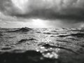 Dark storm clouds gather over a restless ocean with rain falling on the waves under a moody, dramatic sky in a black and white Royalty Free Stock Photo