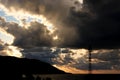 Dark storm clouds at sunset, dark storm clouds with sunrays, mountain and radio tower silhouette over the sea. Climate, storm c Royalty Free Stock Photo