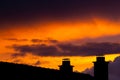 Dark storm clouds during sunset and silhouette of chimney with dramatic sky and vibrant colors Royalty Free Stock Photo