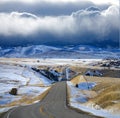 Dark stormy clouds gather above the rural highway running across Montana prairie