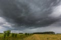 Dark stormy clouds over corn field at summer