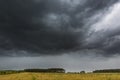 Dark stormy clouds over corn field at summer