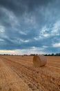 Stormy sky over field with hay bale in the foreground Royalty Free Stock Photo