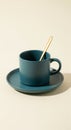Dark teal matte coffee cup and saucer with golden spoon on cream background Royalty Free Stock Photo