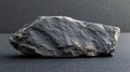 A dark, textured rock on a smooth surface, emphasizing natural minerals and geological features Royalty Free Stock Photo